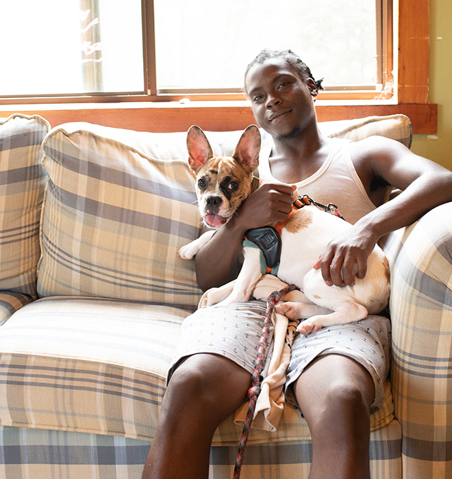 A young man sitting on a couch holding a dog
