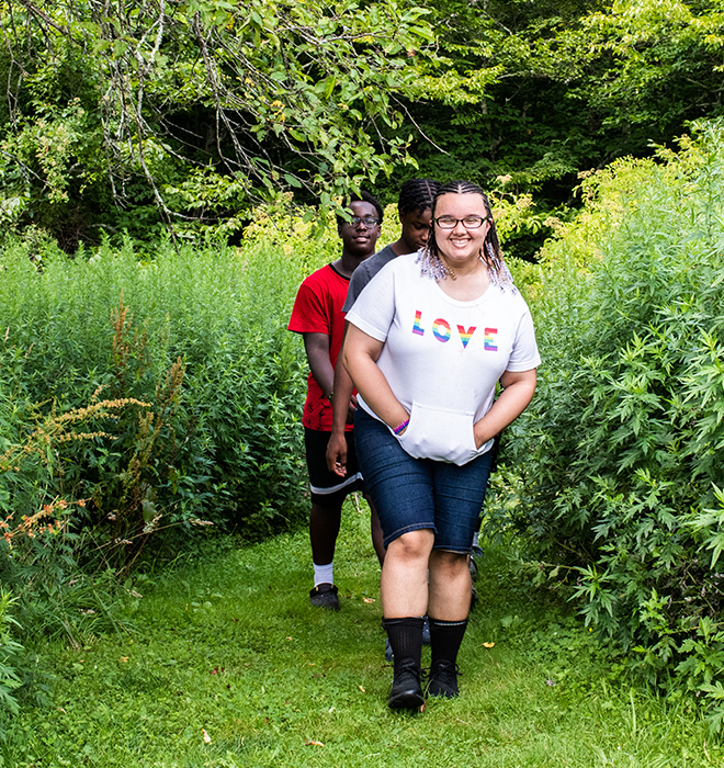 Three campers walking between plants