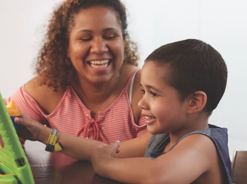 A young boy and an older woman sitting at a table playing a game.
