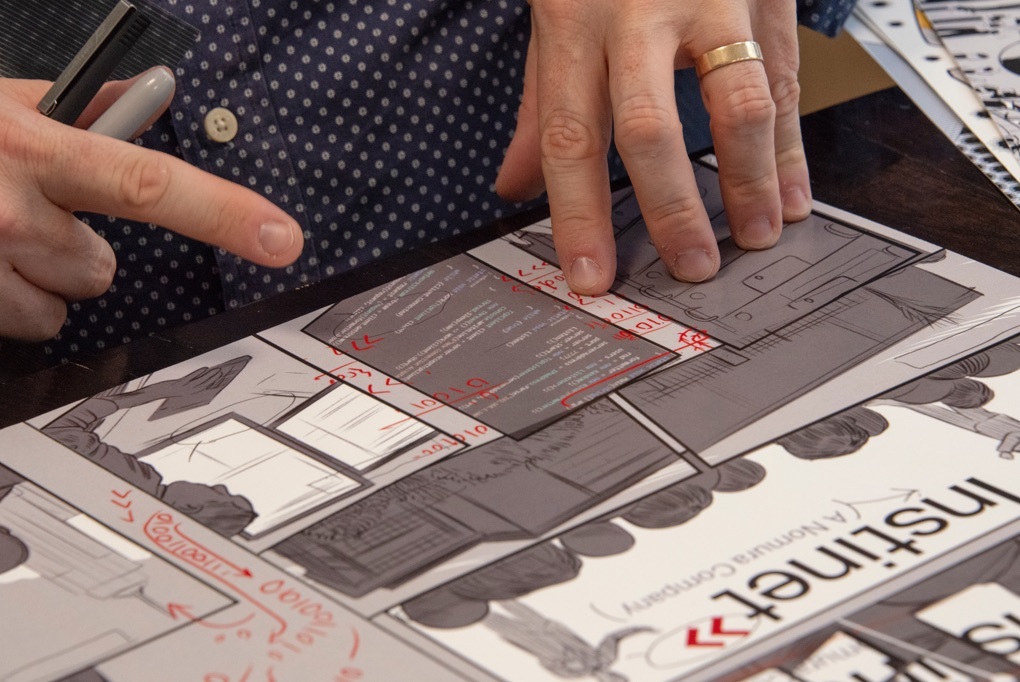 A close up an artists hands over in progress drawings for Instinet's Fintech at Fifty graphic novel.