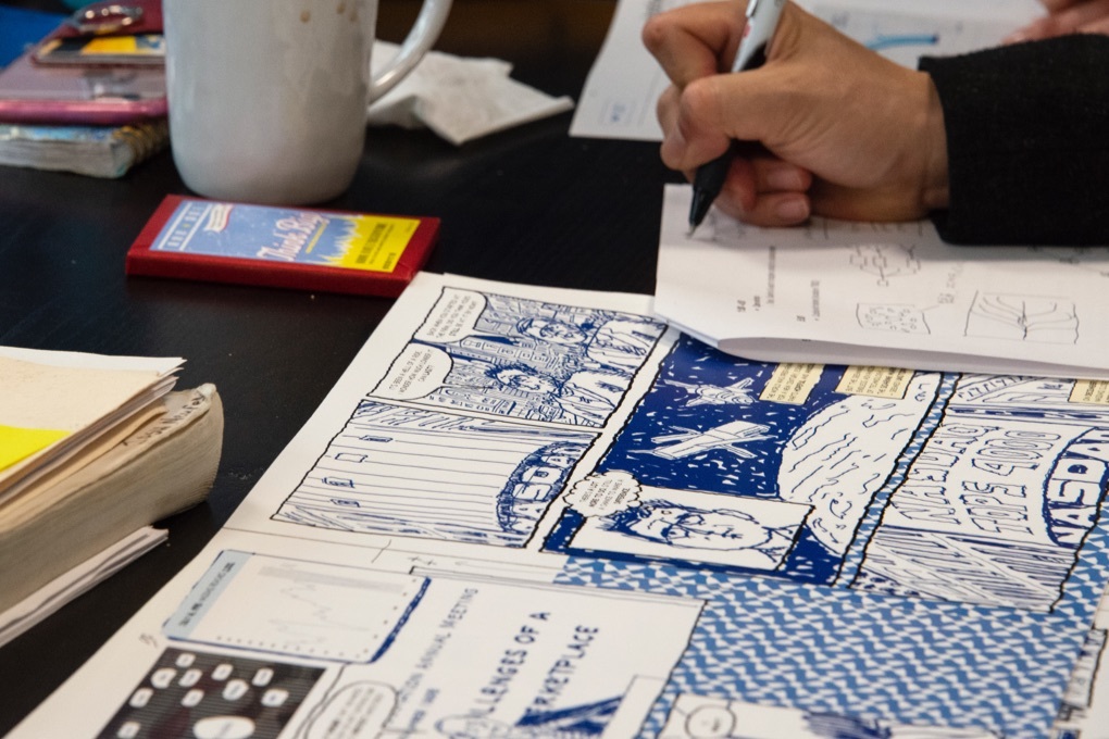 Close up of an illustrator taking notes on draft pages of  Instinet's Fintech at Fifty graphic novel.