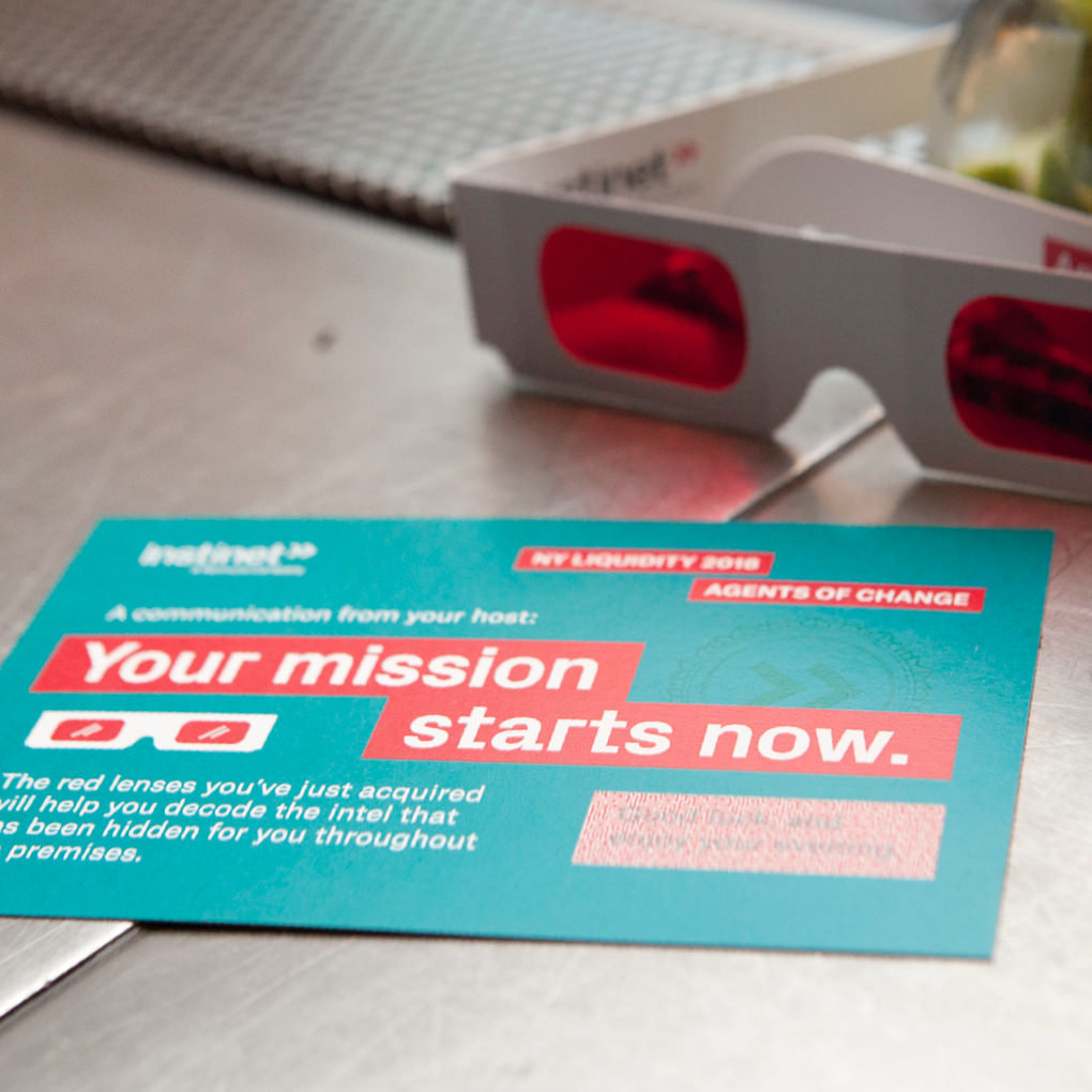 An invitation to an Instinet client event on a tabletop next to a pair of red and blue 3D classes  with the headline Your mission starts now.