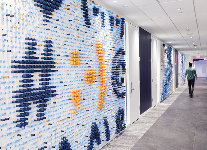 A wall sculpture in the KCG office made of hundreds of colored wooden dowels depicting a hashtag and typographic symbols.