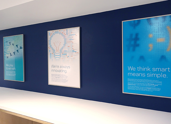 Office wall posters display art and messages from the KCG brand vision book.