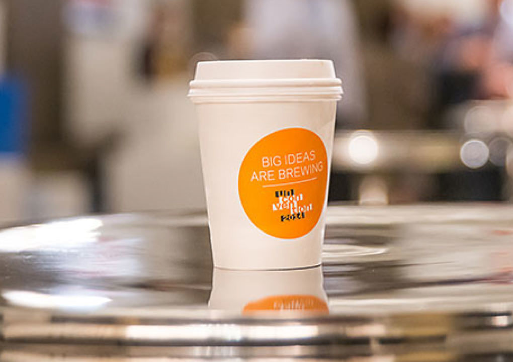 Close up of a 2014 KCG Uncon client event branded coffee cup with the slogan "Big ideas are brewing."