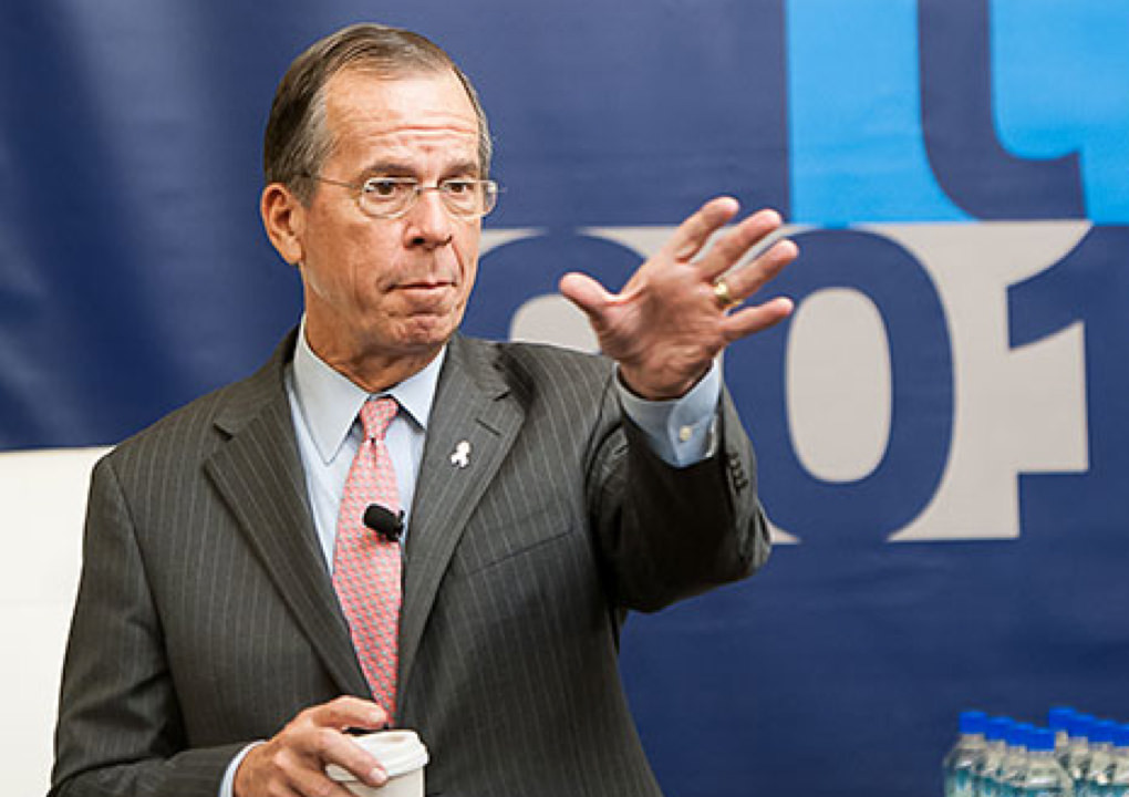 Close up of a presenter gesturing to the audience at the 2014 KCG Uncon client event in front of a large conference banner.