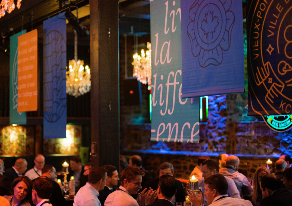 Attendees seated for dinner at the 2017 KCG Uncon client event in a room decorated with event banners.