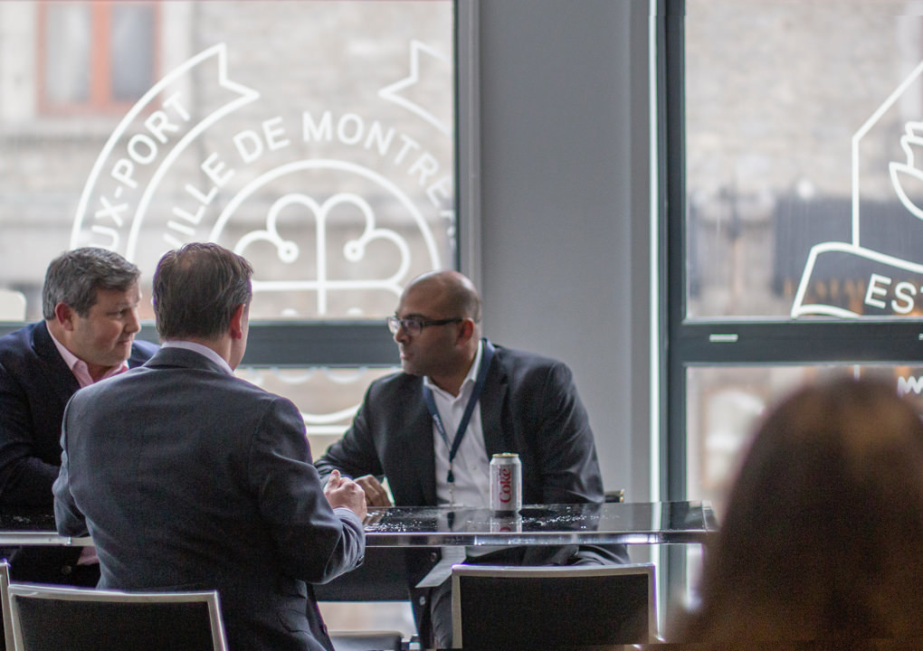 Three attendees on a break at the 2017 KCG Uncon client event in front of windows decorated with the event logo,