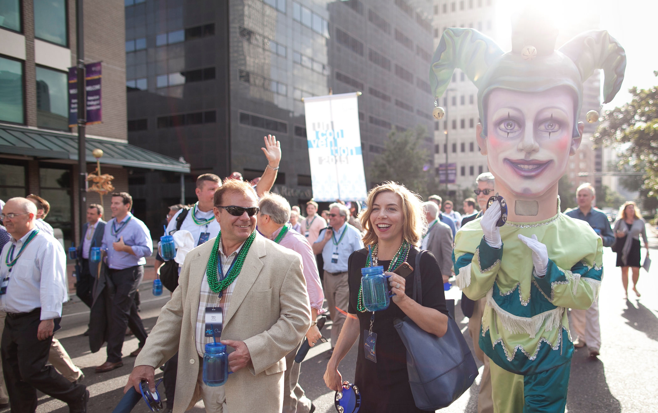 2015 KCG Uncon client event attendees parade on a New Orleans street with a Mardi Gras-style puppet figure.