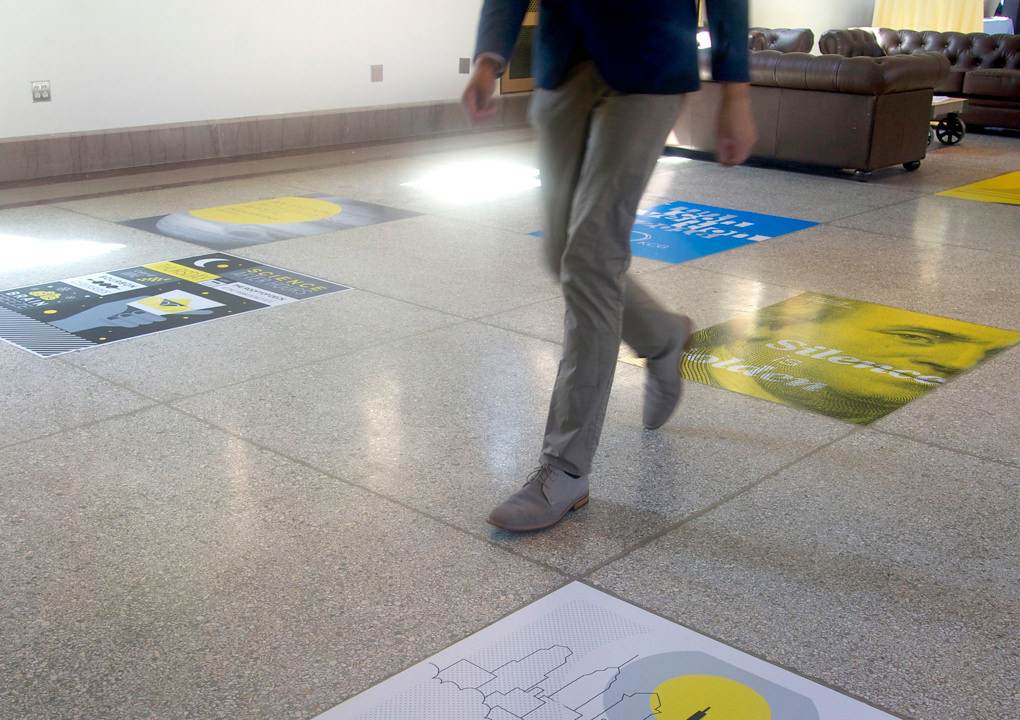 An attendee at the 2016 KCG Uncon client event walking over a terrazzo floor with the large event poster floor stickers.