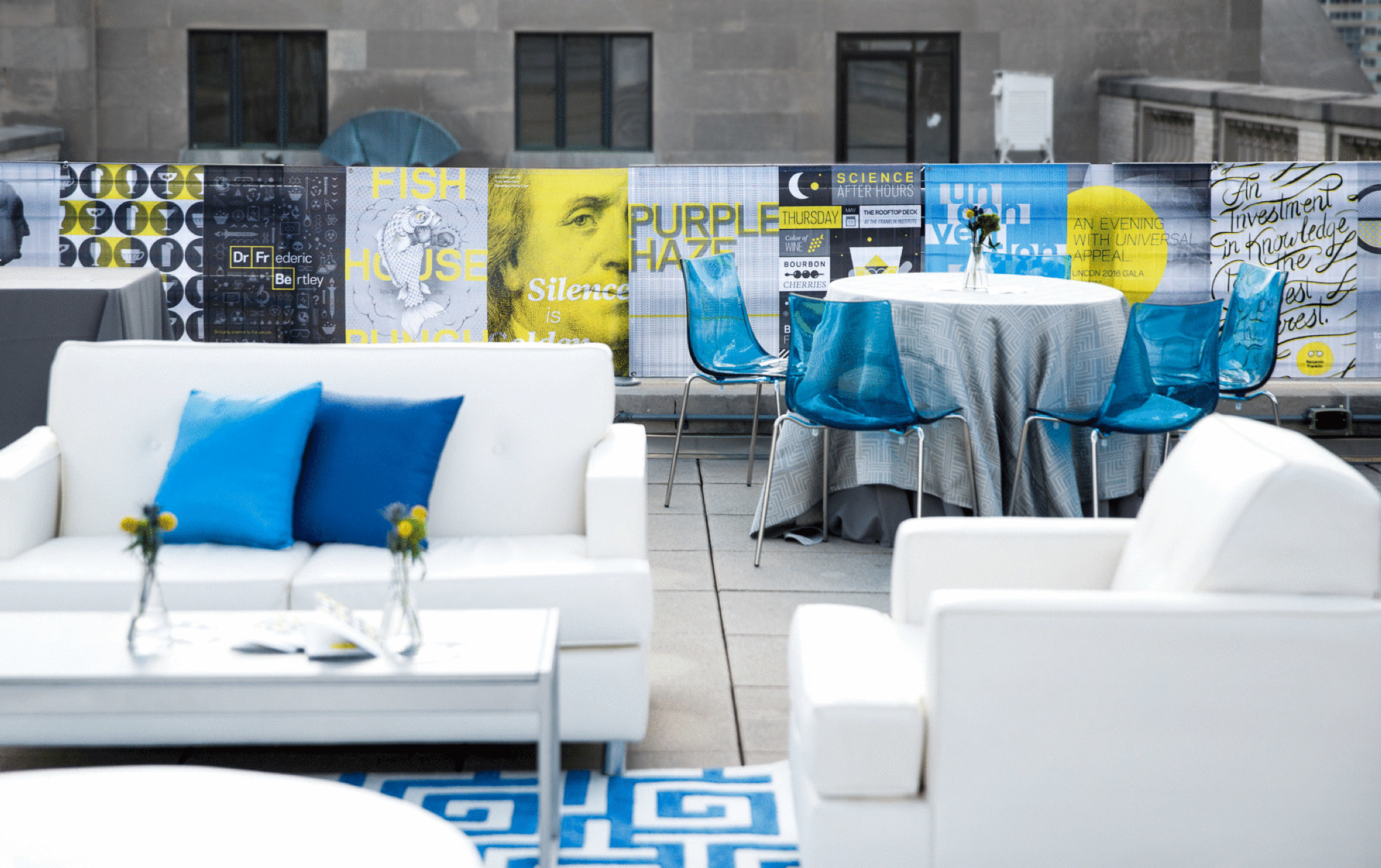 A decorated rooftop reception area at the 2016 KCG Uncon client event rimmed with event posters.