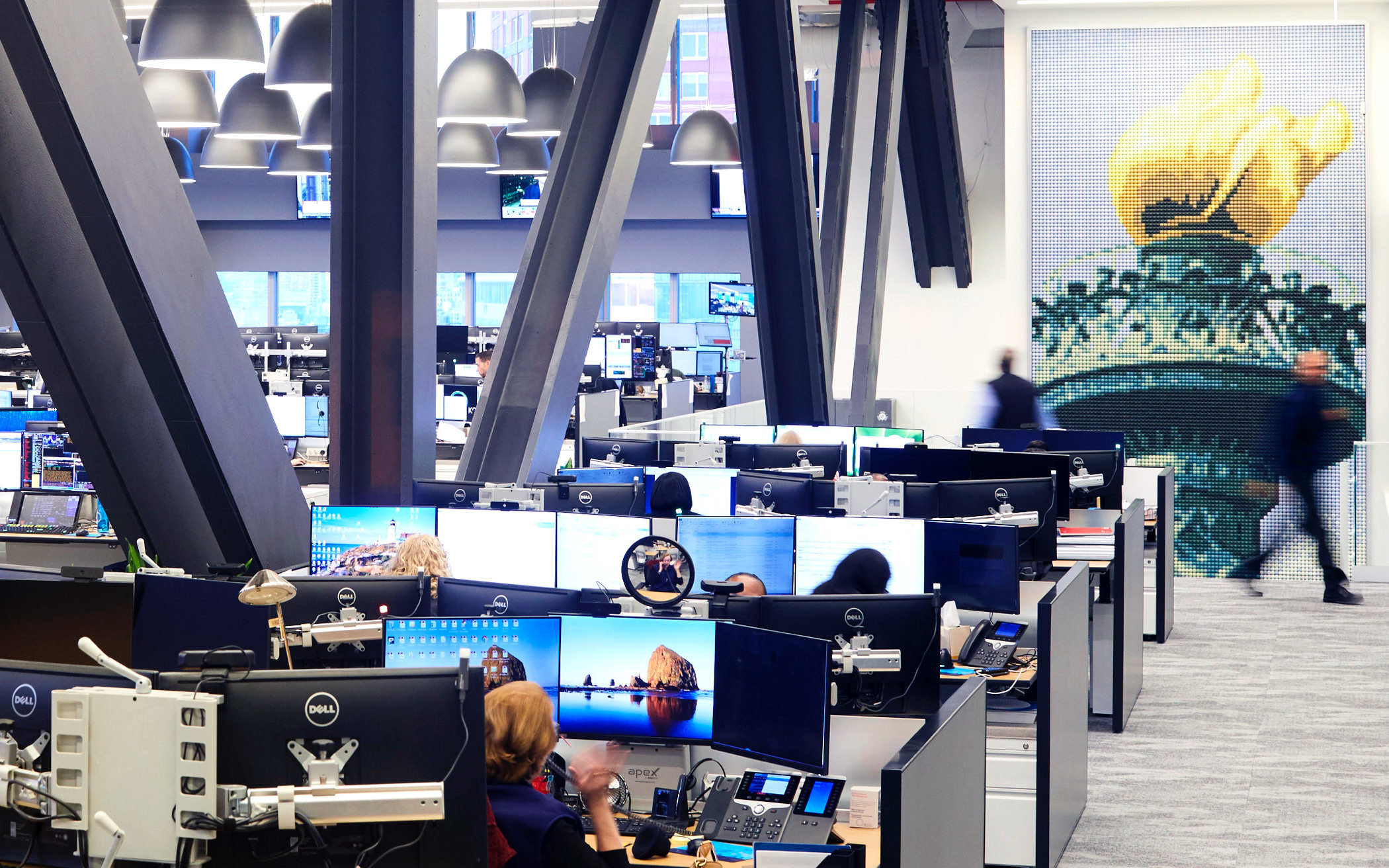 Wide view of computer workstations in KCG's offices. A mural of the torch of the Statue of Liberty is in the background.