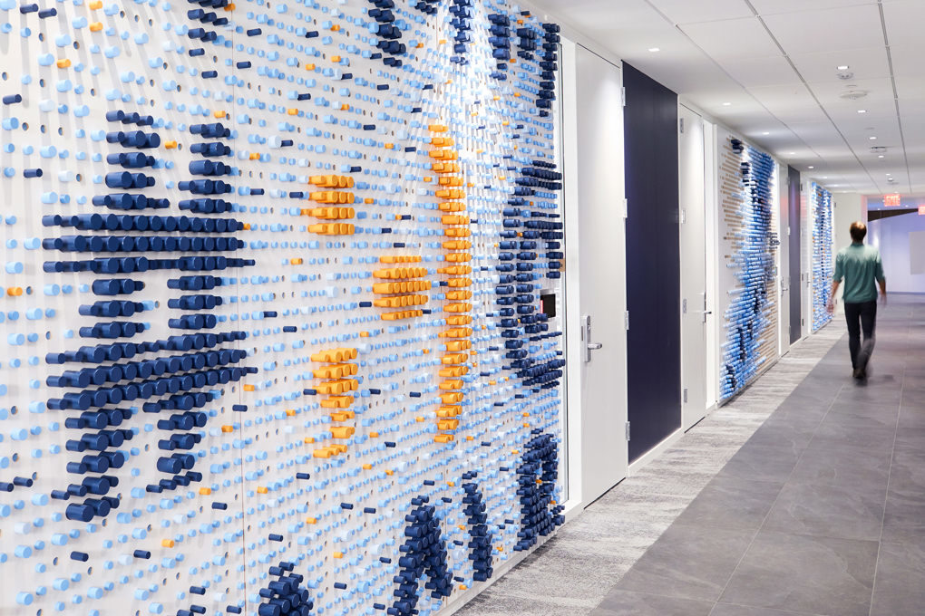 A wall sculpture in the KCG office made of hundreds of colored wooden dowels depicting a hashtag and typographic symbols.