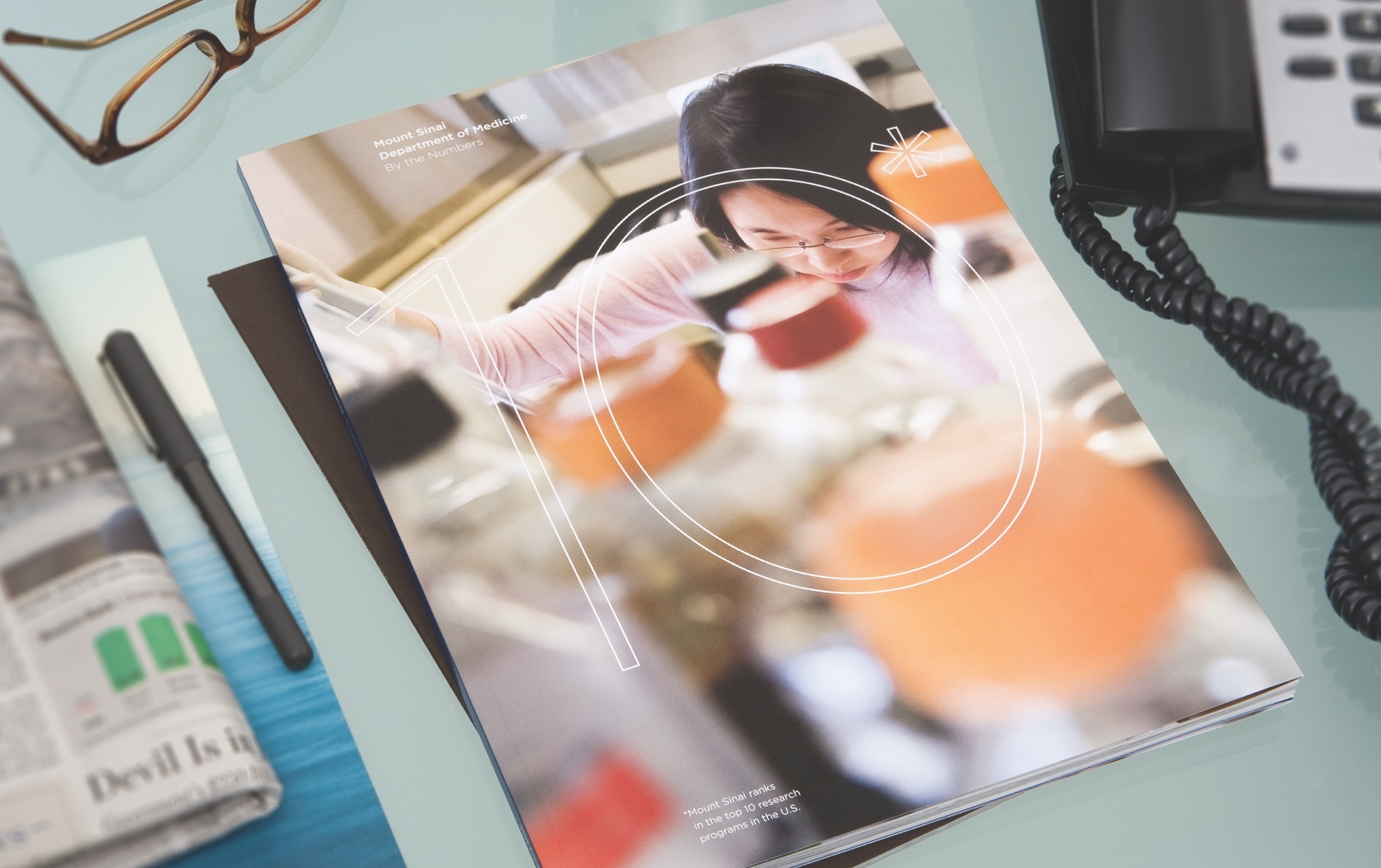 A brochure on a cluttered desktop with an image of a lab worker amid vials and other lab equipment.