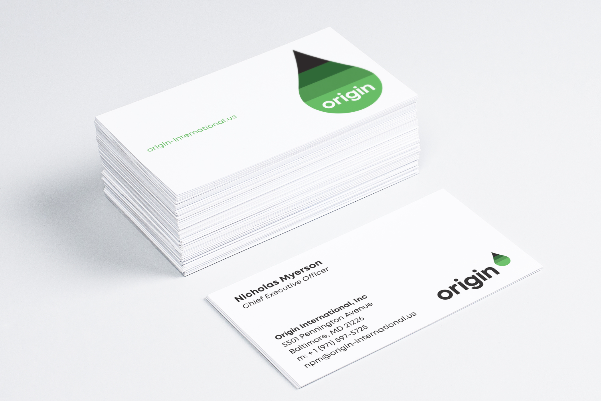 The Origin International logotype and green-gradient droplet symbol painted on white business cards.