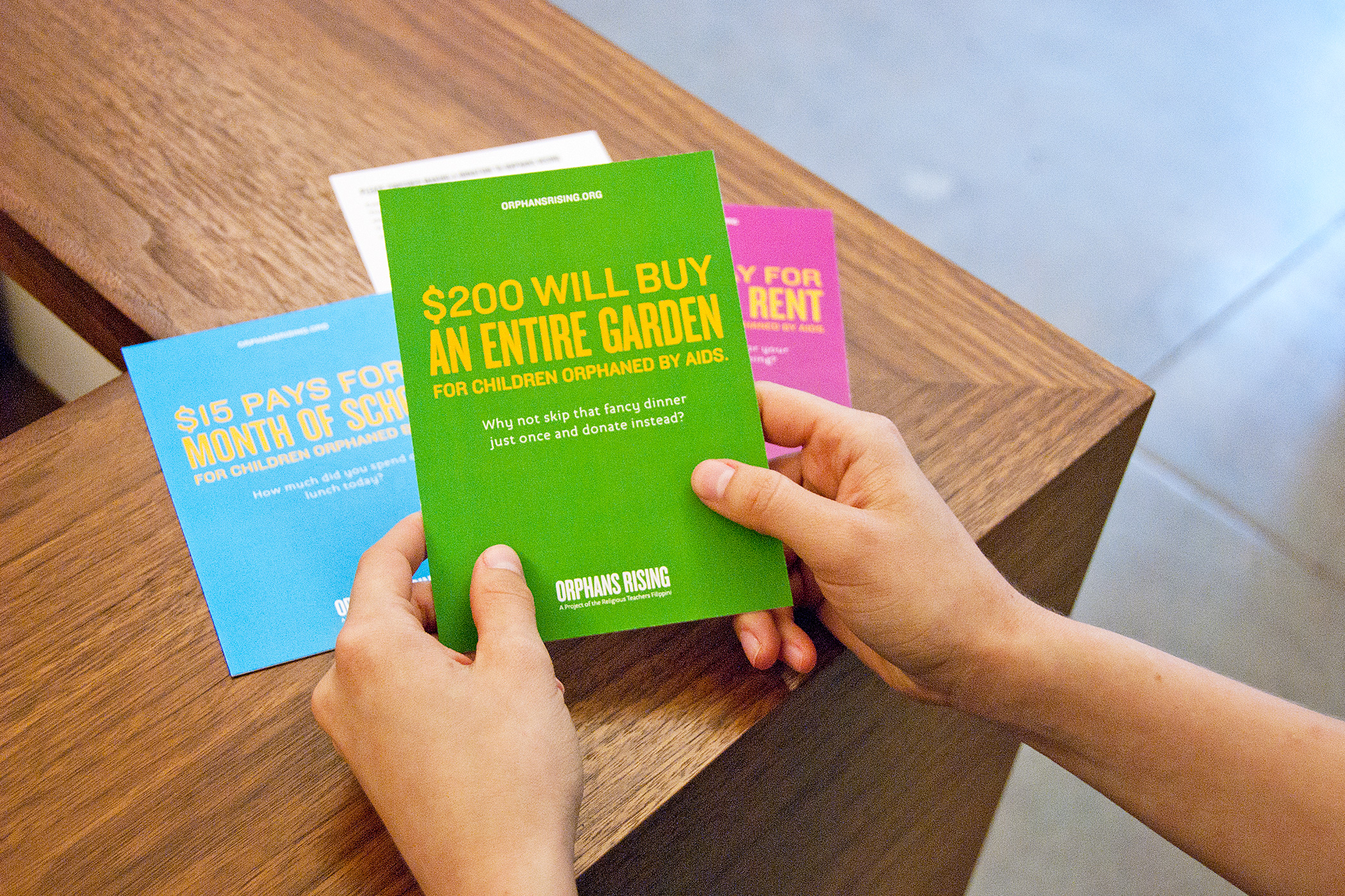 Several brightly colored Orphans Rising fundraising cards with text, such as, $200 will by an entire garden for children orphaned by aids.
