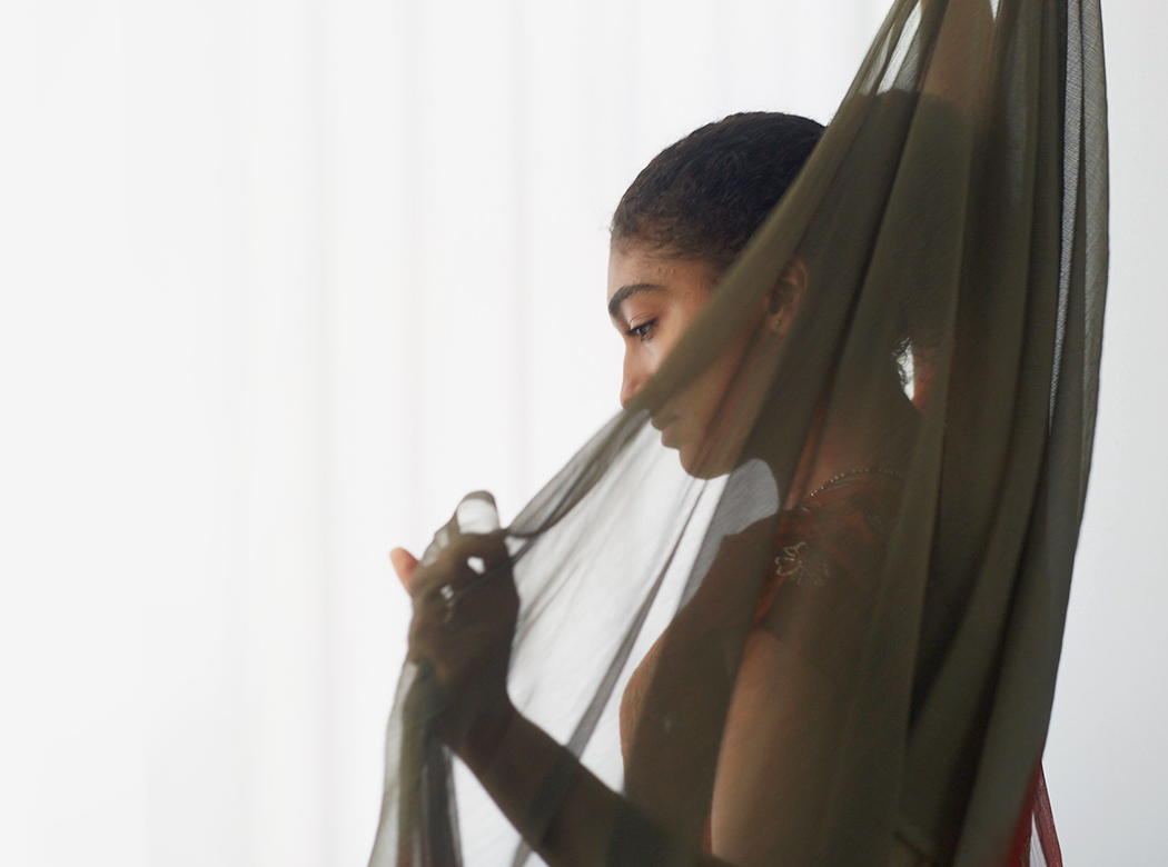 An example of Think Responsive brand photography: a figure is partially covered by a brown see-through overgarment.