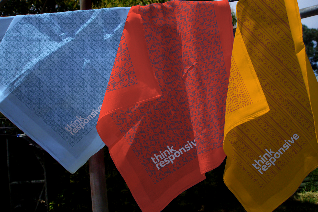 Three Think Responsive branded scarves in blue red and orange printed with the intricate brand line patterns.