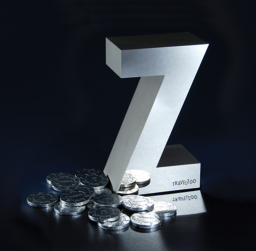 A large, silver letter Z shaped trophy with the Travelzoo logo and a stack of award medallions.