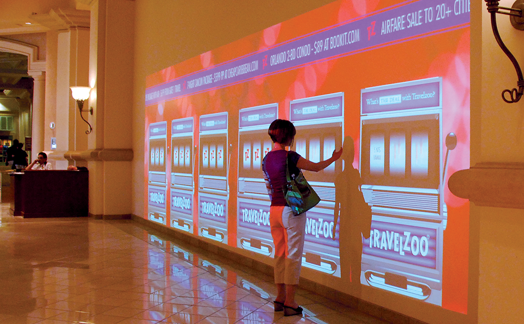A person plays an oversized, Travelzoo-branded interactive virtual slot machine at the Travelzoo awards in Las Vegas.