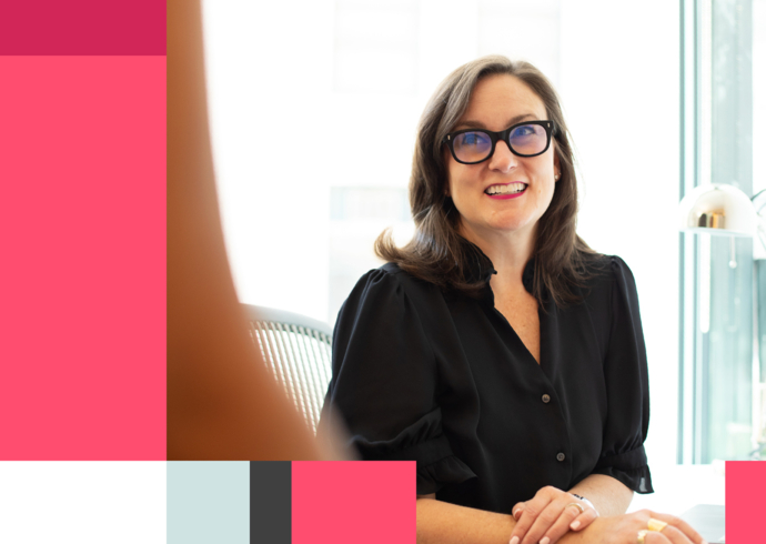 Thinkso founder Elizabeth Amorose sits at a desk, looking up and smiling towards someone out of frame.