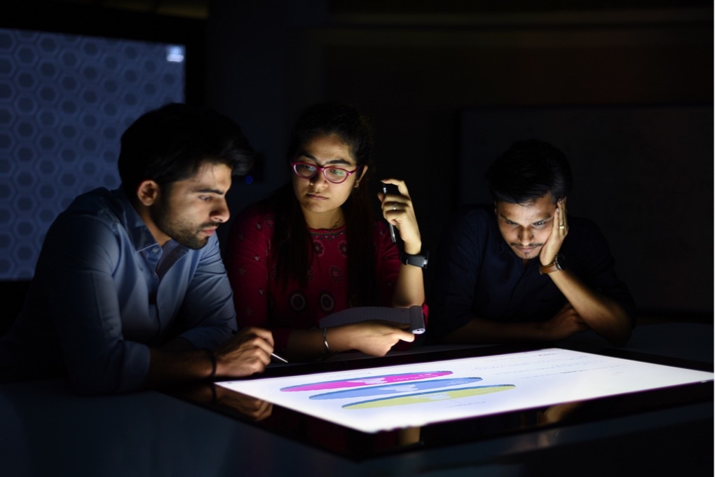 Three Mindtree workers working on large touch-screen