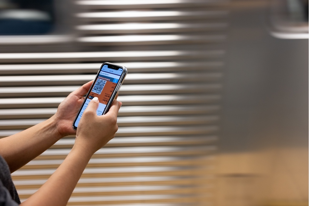 Figure holding smartphone displaying QR code