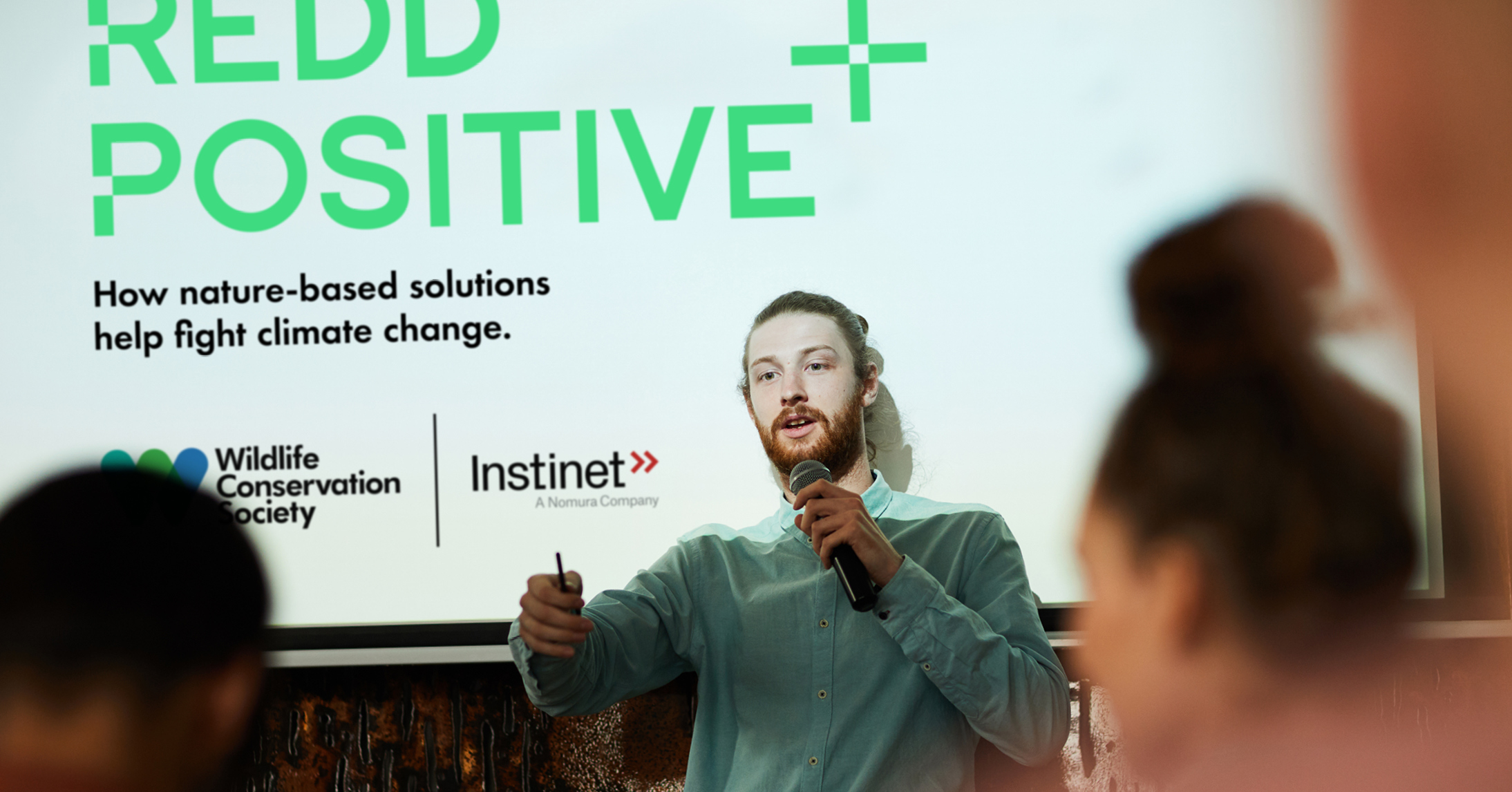 A WCS staff person in front of a projected presentation about Redd Positive speaking to an audience.